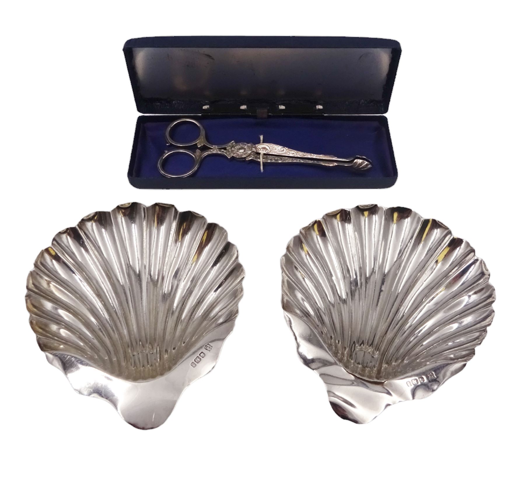 Pair of late Victorian silver shell butter dishes, upon three bun feet, hallmarked James Deakin & Sons, Sheffield 1900, together with a pair of late Victorian scissor action sugar nips, engraved with foliate decoration, hallmarked Sheffield 1897, maker's mark indistinct