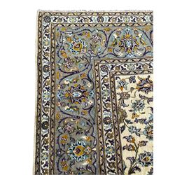 Persian Kashan ivory ground carpet, the busy field decorated with scrolling and interlaced leafy branches and palmettes, trailing branch border with repeating stylised plant motifs, within floral pattern guard stripes 