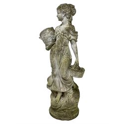 Weathered and painted cast stone garden statue, in the form of an Italian maiden carrying baskets with gathered flora and berries, on a shaped ovoid base