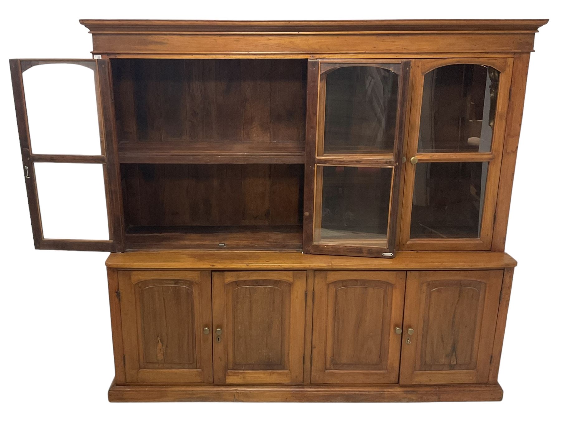 Mid-to-late 20th century Burmese teak wall cabinet, four glazed doors over four panelled doors, on moulded plinth base 