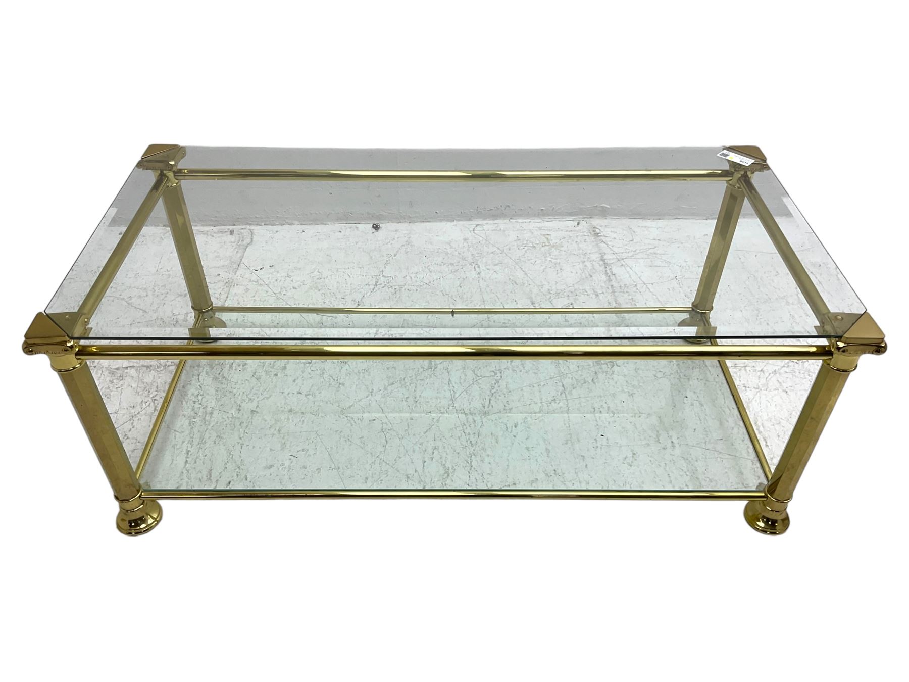 Gilt metal and bevelled glass two-tier coffee table, the faceted supports with Ionic Capitals