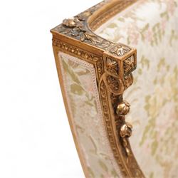 Late 19th century French gilt wood and gesso enclosed armchair, the cresting carved with floral bouquets over foliate moulding, upholstered in floral pattern fabric with repeating pattern, down-swept arms with scrolled acanthus leaf terminals, on turned and fluted feet carved with foliage 