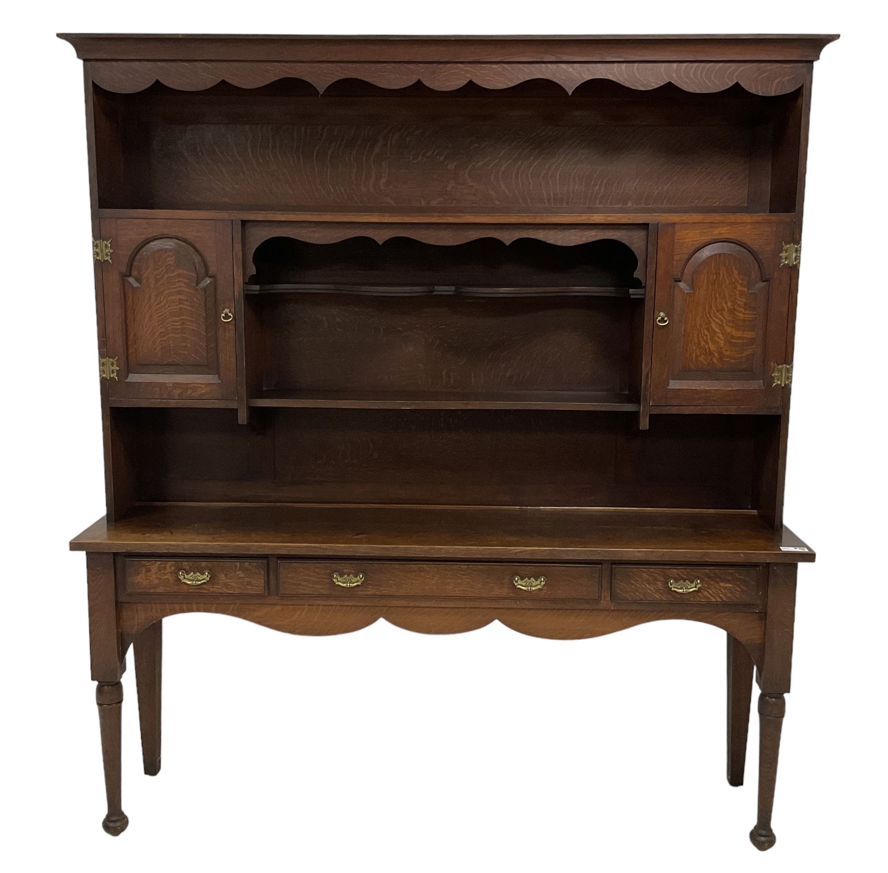 Early 20th century Georgian design oak dresser, projecting cornice with shaped apron over a three-tier plate rack with flanking fielded spice cupboards, the base fitted with three drawers, on turned supports