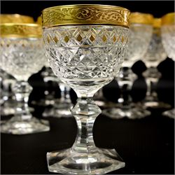 Part suite of crystal drinking glasses comprising thirteen red wine glasses and twelve white wine glasses, all with foliate gilt banding, hobnail cut bowls and hexagonal faceted stems, in the style of Moser 