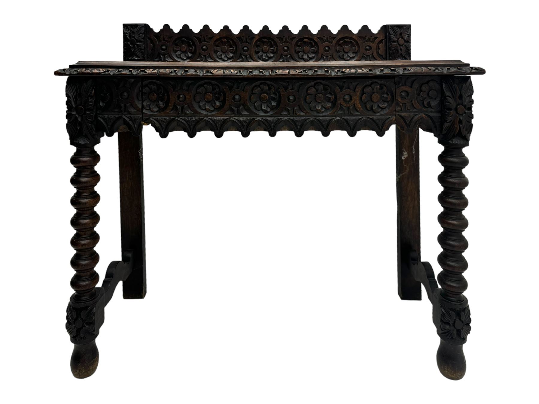 Victorian Gothic revival style carved oak console table, rectangular top with carved edge and raised back gallery, over deeply carved apron with floral and foliate motifs and central drawer, barley twist front supports and plain rear supports united by shaped stretchers, on front bun feet