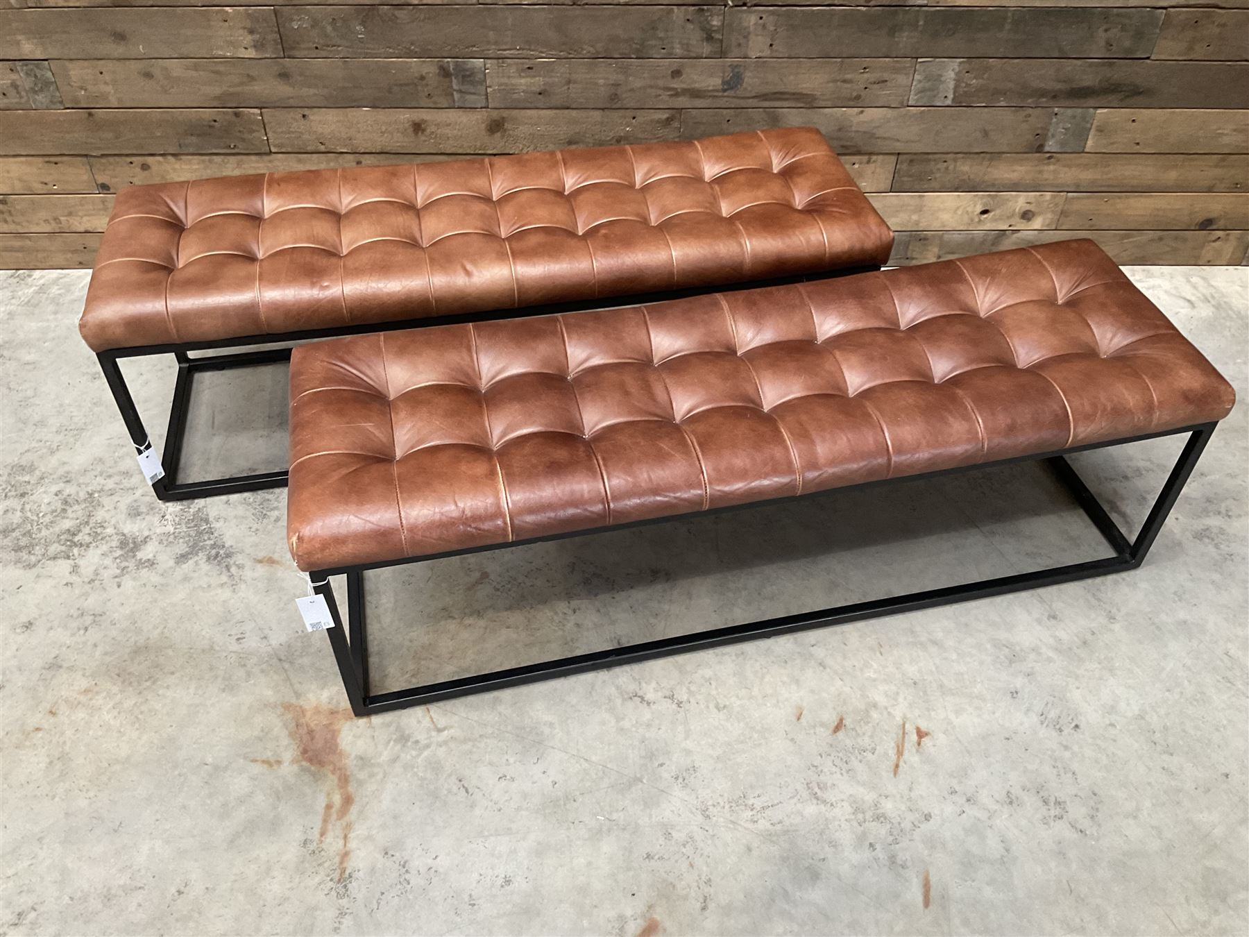 Two rectangular metal framed benches, upholstered in buttoned tan leather