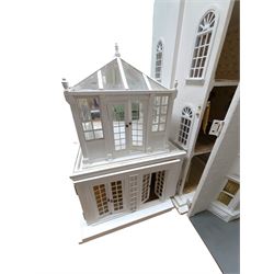 Large three storey modern dolls house, painted white with latticed windows, grey roof and metal fencing, with decorated interior, together with two dolls house garden rooms and two conservatories