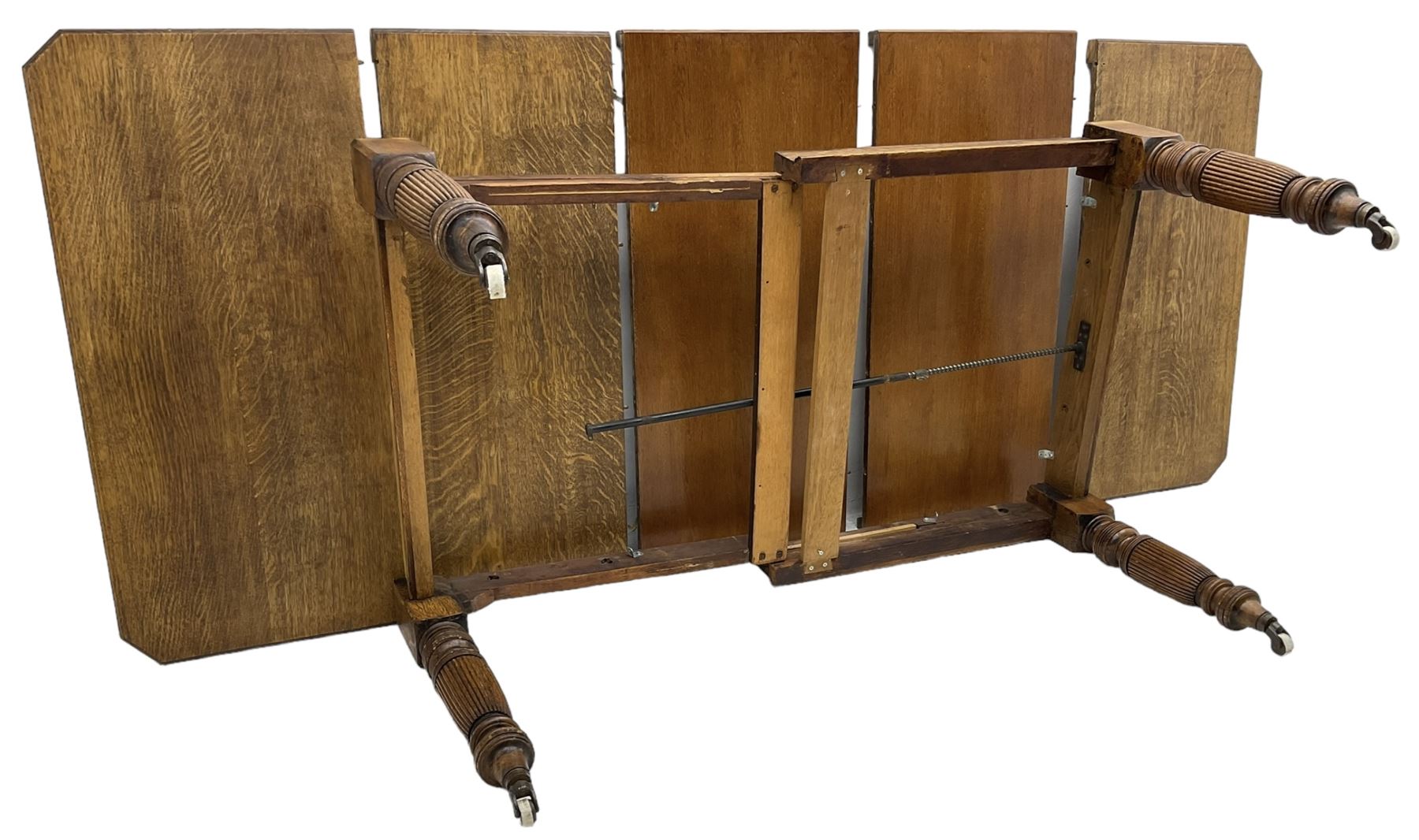 Late Victorian oak telescopic extending dining table, rectangular moulded top with canted corners, three additional leaves, on turned and reeded supports with brass and ceramic castors