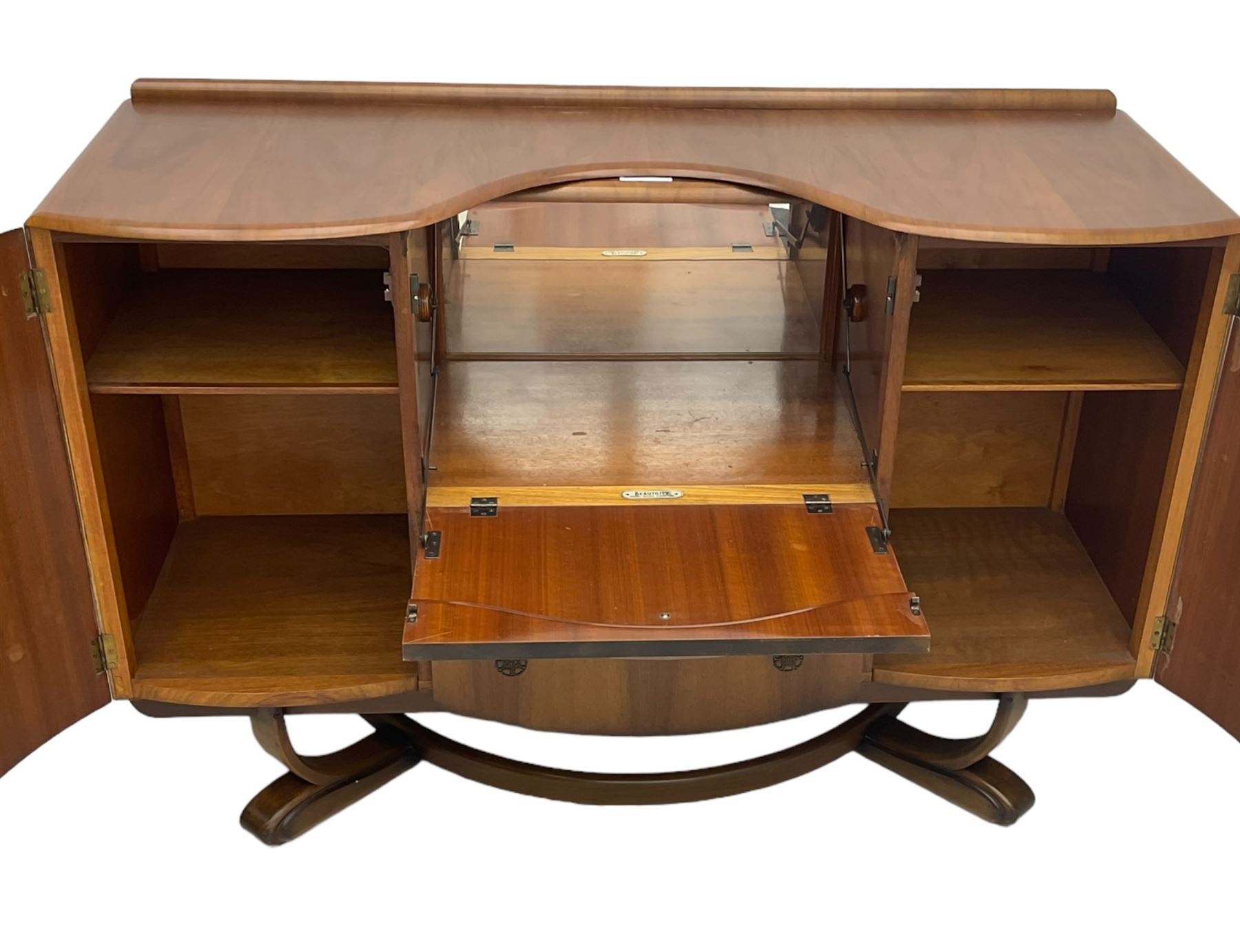 Beautility - mid-20th century walnut sideboard, fall-front with sliding top enclosing mirror interior, fitted with two drawers and flanking cupboards, on sledge feet with curved stretchers 