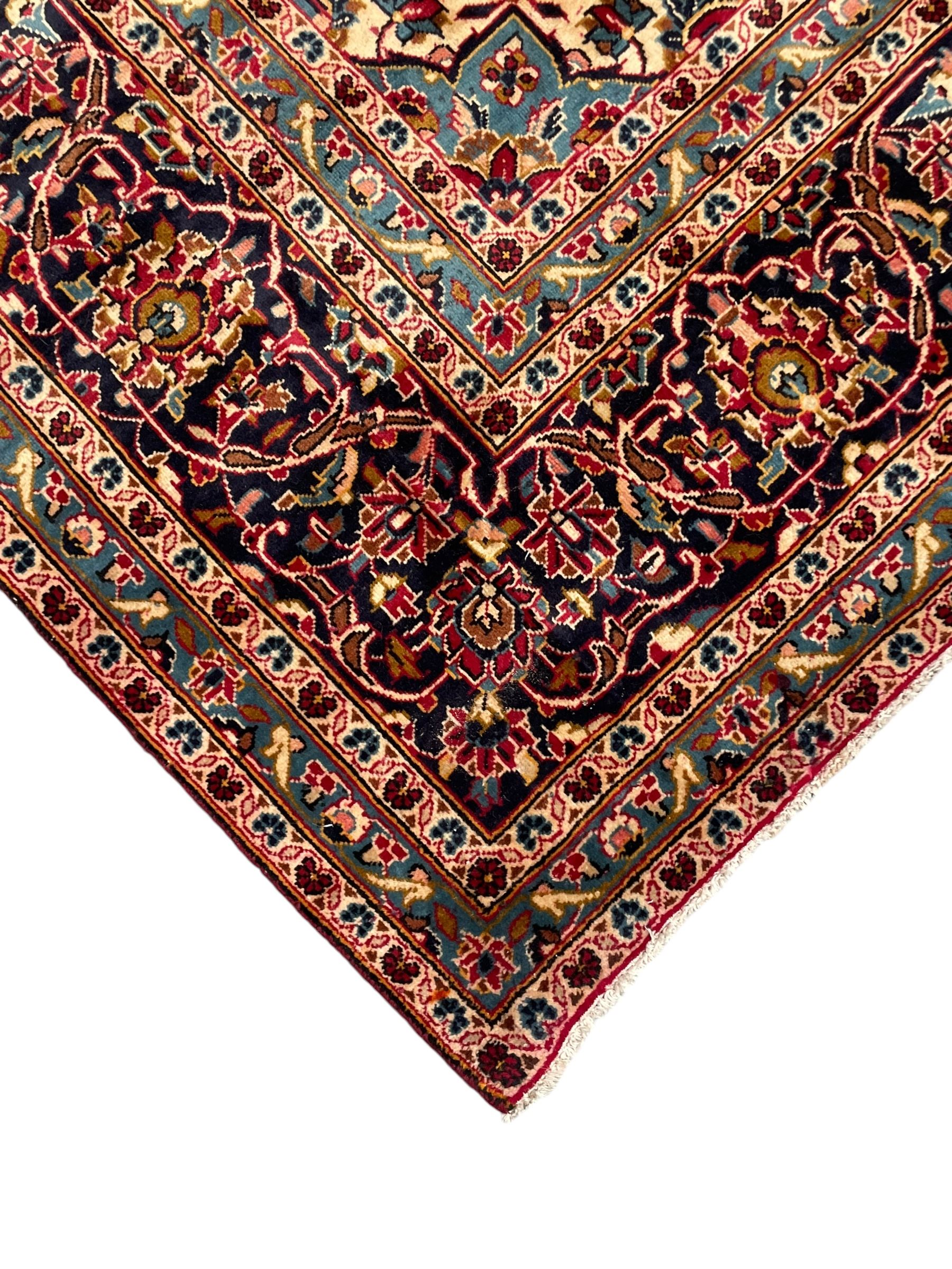 Persian Kashan crimson ground carpet, floral pattern pole medallion surrounded by trailing branches with foliate motifs and palmettes, scrolling border decorated with stylised plant motifs, within multiple guard stripes