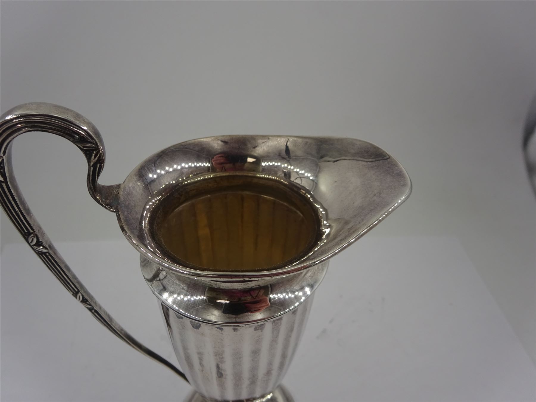 Early 20th century silver cream jug, of helmet form with faceted body and scroll handle, upon stepped circular foot, hallmarked Walker & Hall, date mark indistinct, H16.5cm