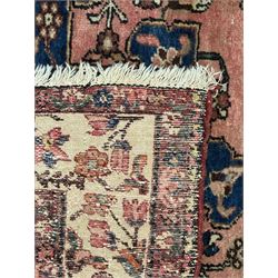 Persian Hamadan ground rug, central medallion design with a salmon pink field, accentuated by navy blue spandrels, surrounded by a stylised floral border in cream and blue tones