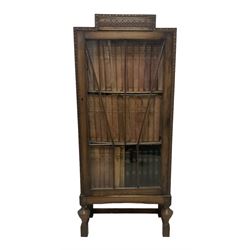 Edwardian oak bookcase, stepped top decorated with beading and stylised floral frieze, single astragal glazed door enclosing encyclopaedias and other books, on turned front feet united by plain stretchers 