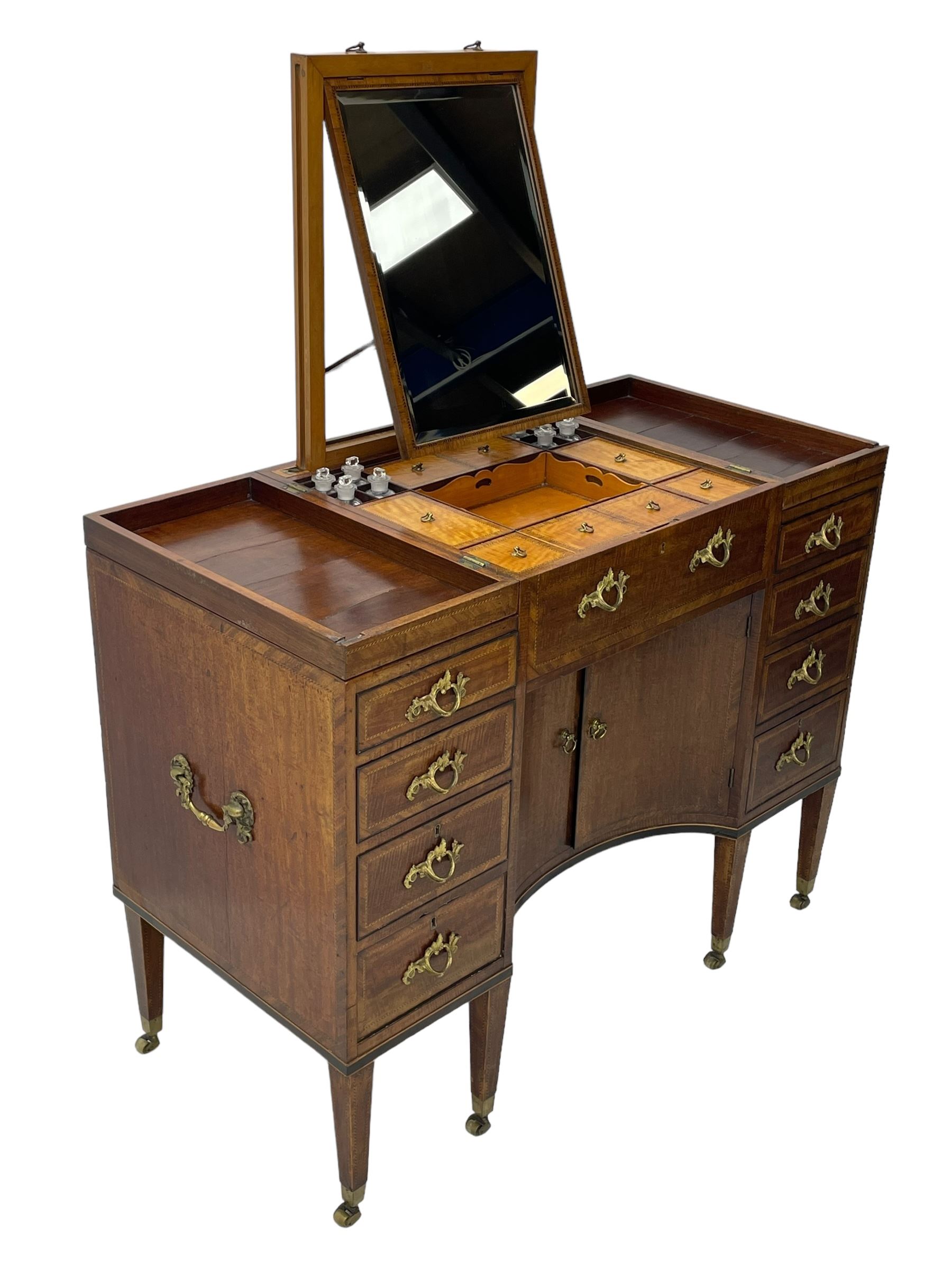 Late 19th century mahogany and satinwood dressing chest, the raised middle section hinges to reveal an interior fitted with lidded compartments, removable tray, single drawer and glass scent bottles, lift-up bevelled mirror with adjustable hinged mechanism, fitted with a further eight cock-beaded graduating drawers and curved kneehole with double cupboard, square tapering supports on brass cups and castors, inlaid throughout with checkered stringing, ornate Rococo cast gilt metal handles