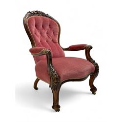 Victorian carved walnut open armchair, foliate carved cresting rail over butted back and sprung seat, upholstered in pink velvet scrolled arm terminals with moulded scrolling vines terminating to cabriole supports and ceramic castors