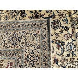 Persian Nain ivory ground carpet, central indigo medallion, the busy floral field decorated with scrolling vines and flower heads in shades of blue, beige, and red, wide guarded border with repeating palmettes and foliate motifs