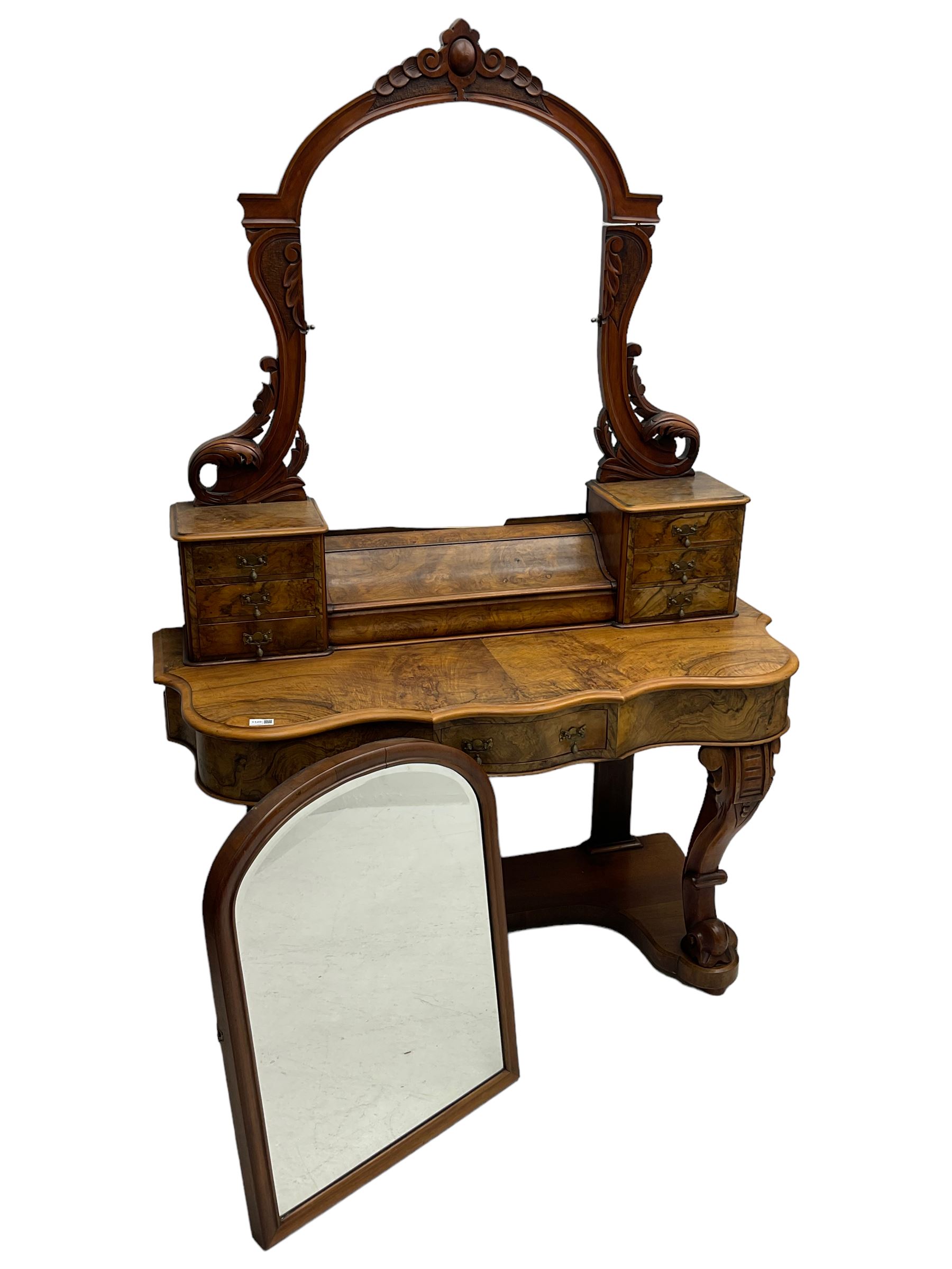 19th century figured walnut dressing table, the raised bevelled mirror back in carved foliage frame with scrolled terminals, fitted with central hinged compartment flanked by small trinket drawers, serpentine moulded top over single frieze drawer, on cabriole supports united by a platform base