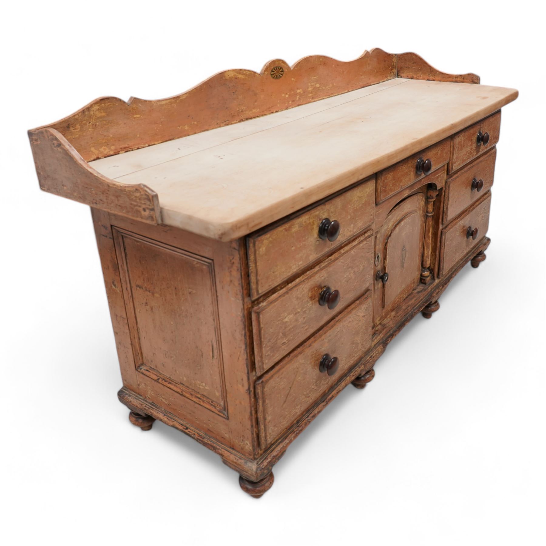 Victorian scumbled pine and sycamore dresser base, the sycamore top framed within shaped gallery, fitted with seven drawers and central cupboard enclosed by half columns mounts, on turned feet 