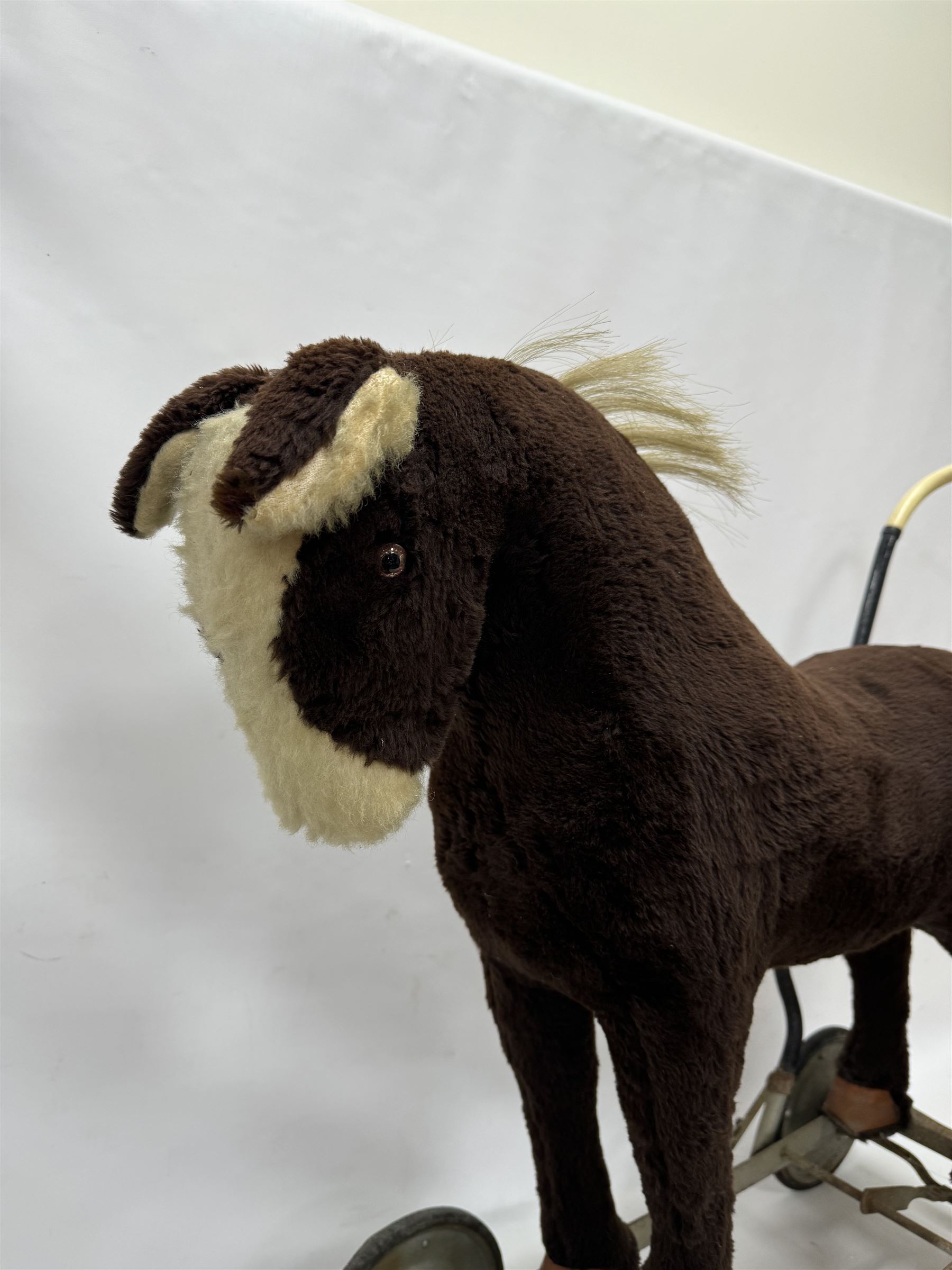 1920s/30s Panurge Pets push-a-long horse, with brown mohair body and white face, horse hair mane and tail and leather hooves, mounted upon a metal with rubber and metal wheels, including handle H71cm