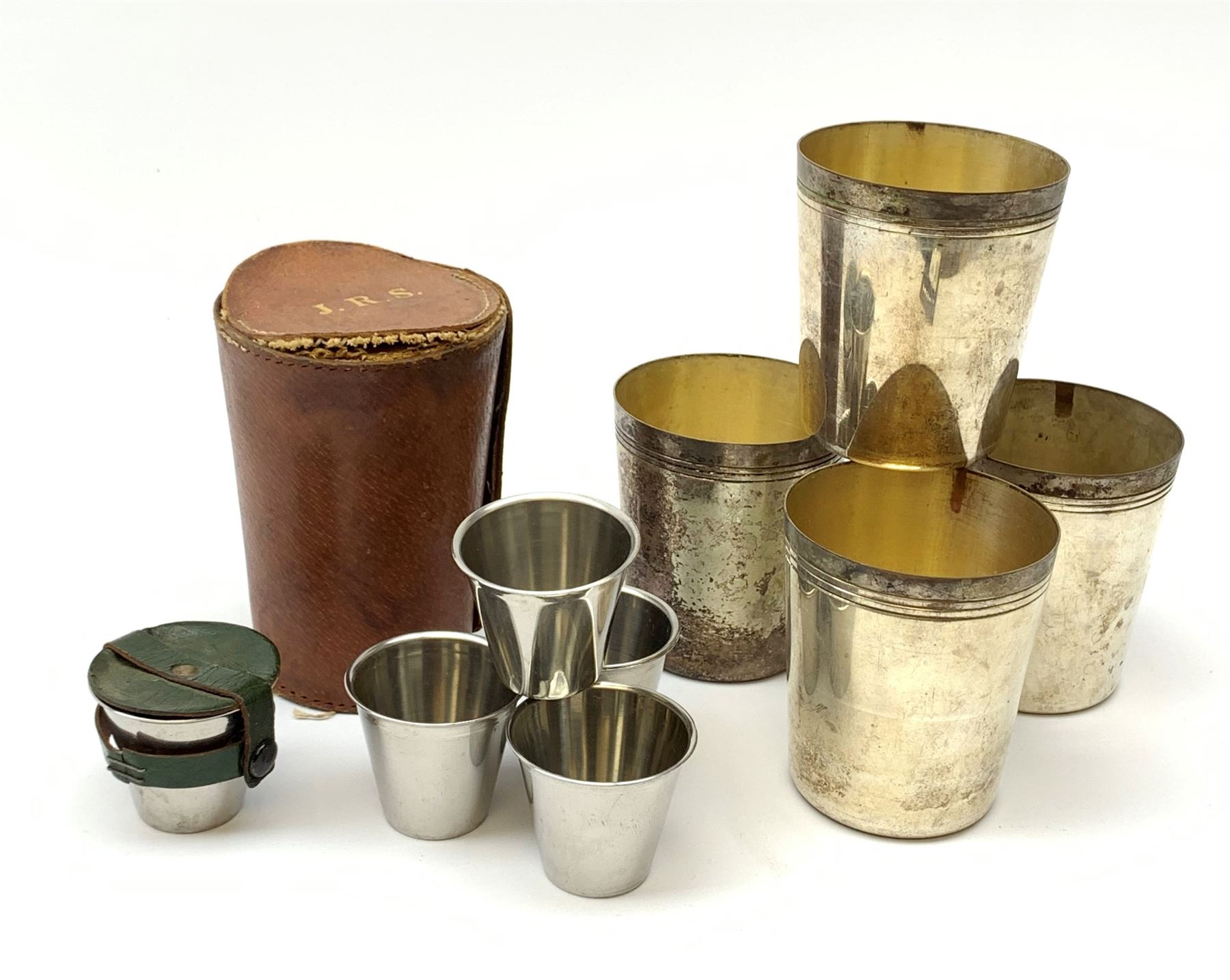 A silver plated set of four stirrup cuts with gilded interiors, by P H Vogel & Co, in brown leather case tooled in gilt J.R.S., each cup marked beneath P.H.V&Co Silver Plated Made in England, H8.5cm D7.5cm, together with a set of six stainless steel Swedish stirrup cups by Rostfritt, in green leather holder, each cup marked beneath Rosfritt, H4.5cm D5cm.