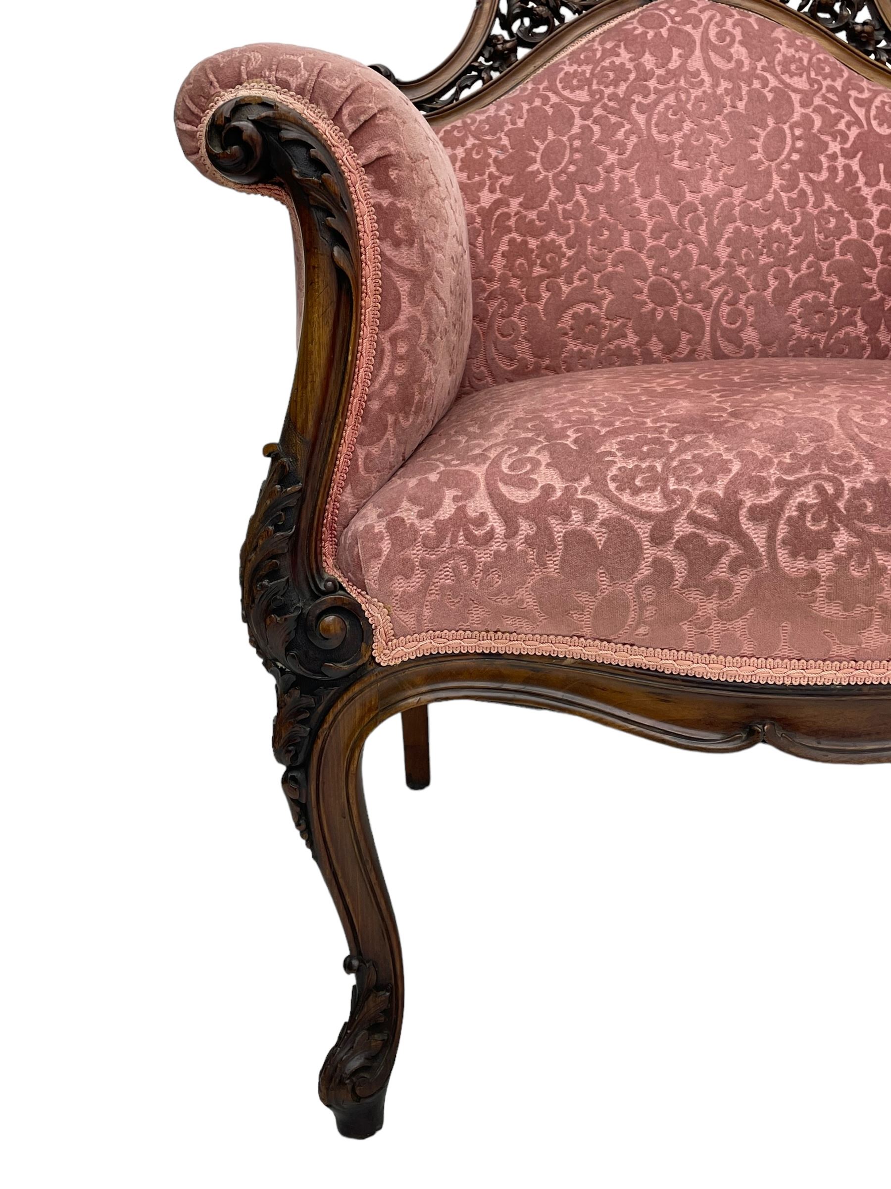 Late 19th century carved walnut framed armchair, the upper spandrels pierced and carved with curled acanthus leaves, upholstered in pink foliate pattern fabric, acanthus leaf carved and scrolled arm facias terminating to cabriole supports, leaf carved terminals 