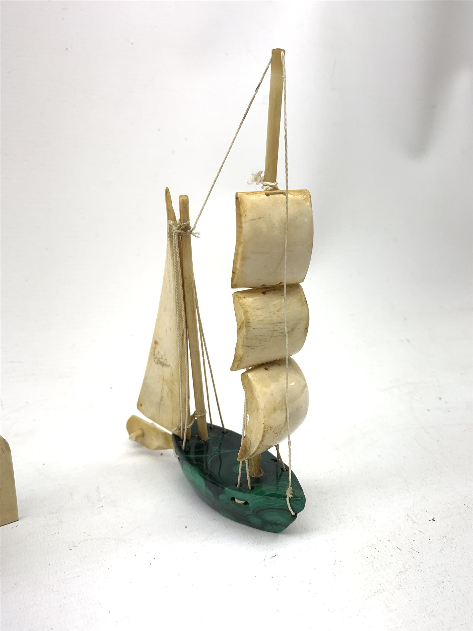 A Japanese carved ivory model of a sailing boat, surmounted by three carved figures (a/f), L22.5cm, together with a smaller sail boat with malachite hull and ivory sails and rudder, H18cm. 