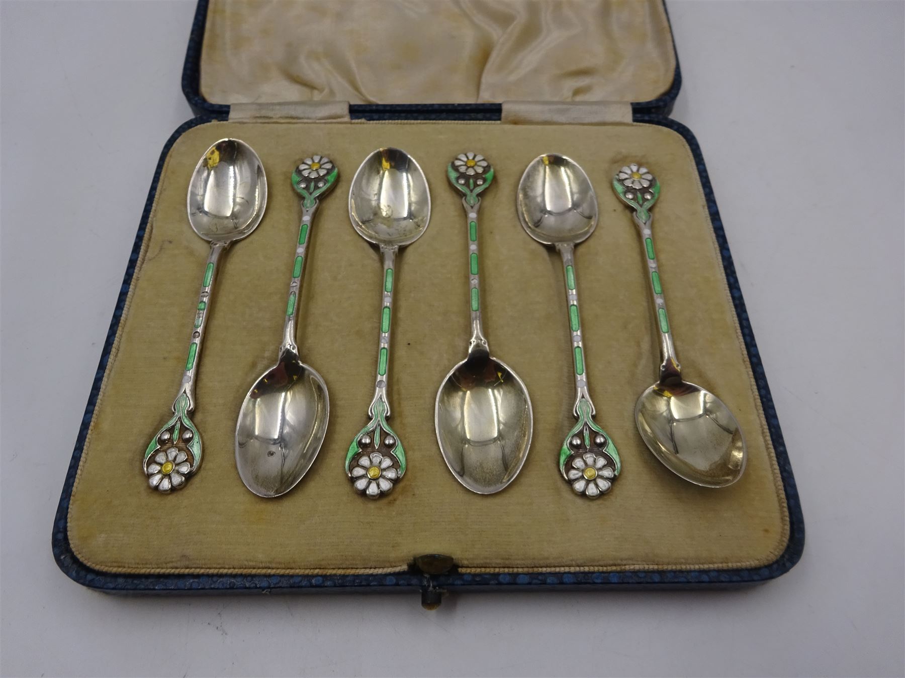 Set of six 1930s silver coffee spoons, each with enamelled daisy decoration to terminal with green and white enamelled stems, hallmarked Turner & Simpson Ltd, Birmingham 1936, contained within fitted case