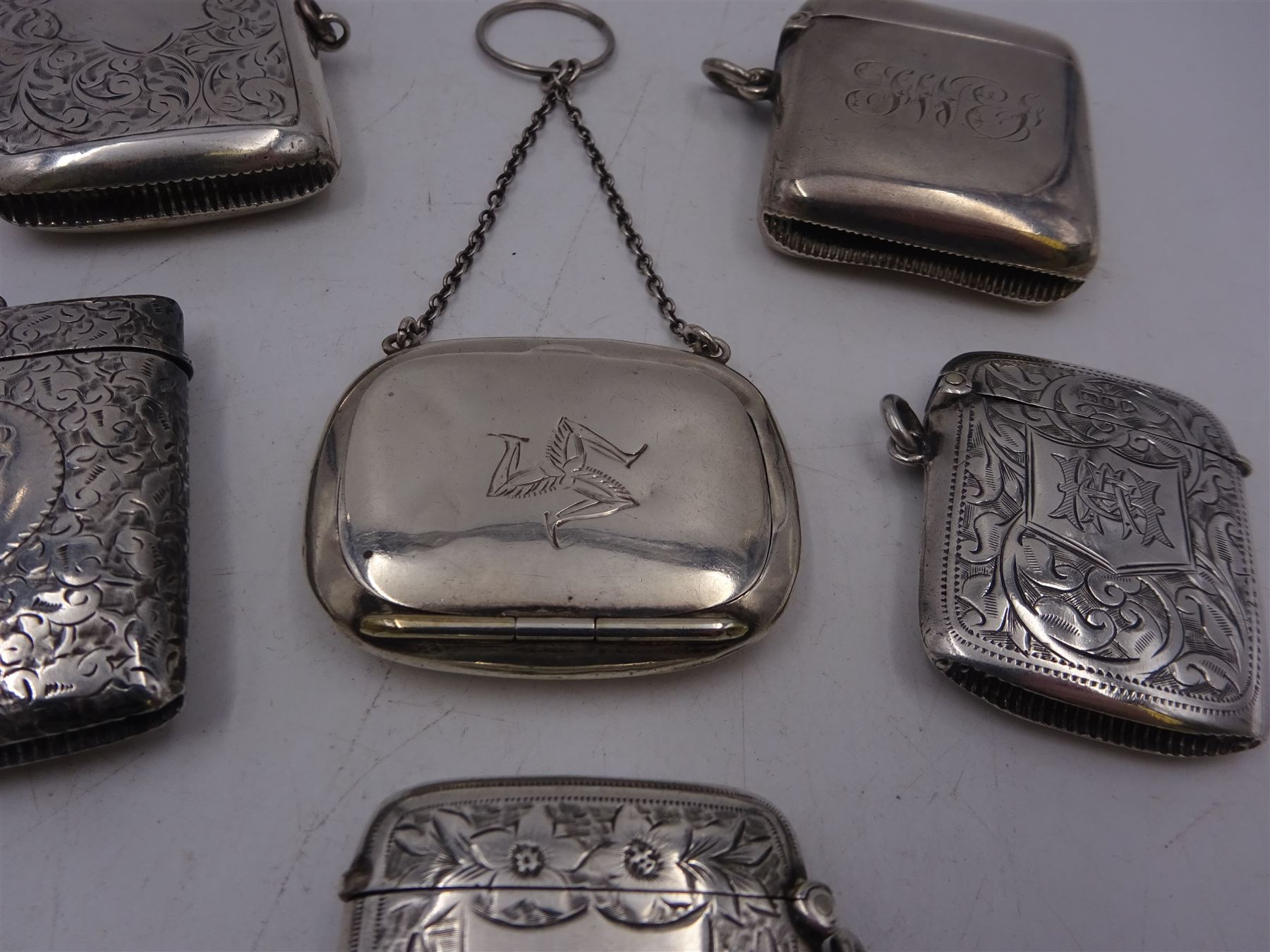 1920s silver miniature purse, engraved with triskelion symbol to hinged cover, hallmarked Adie & Lovekin Ltd, Birmingham 1920, together with five early 20th century silver vesta cases, all of typical form, engraved with foliate and scrolling details, all hallmarked