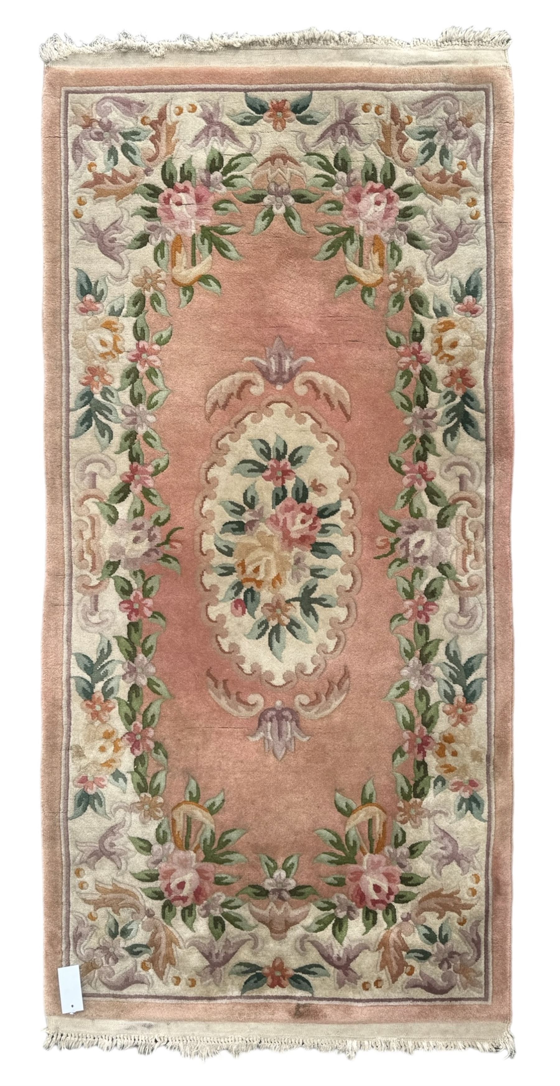 Chinese Aubusson design pink ground rug, the field decorated with an oval medallion filled with floral motifs in pastel shade, surrounded by floral garlands and foliate scrolls