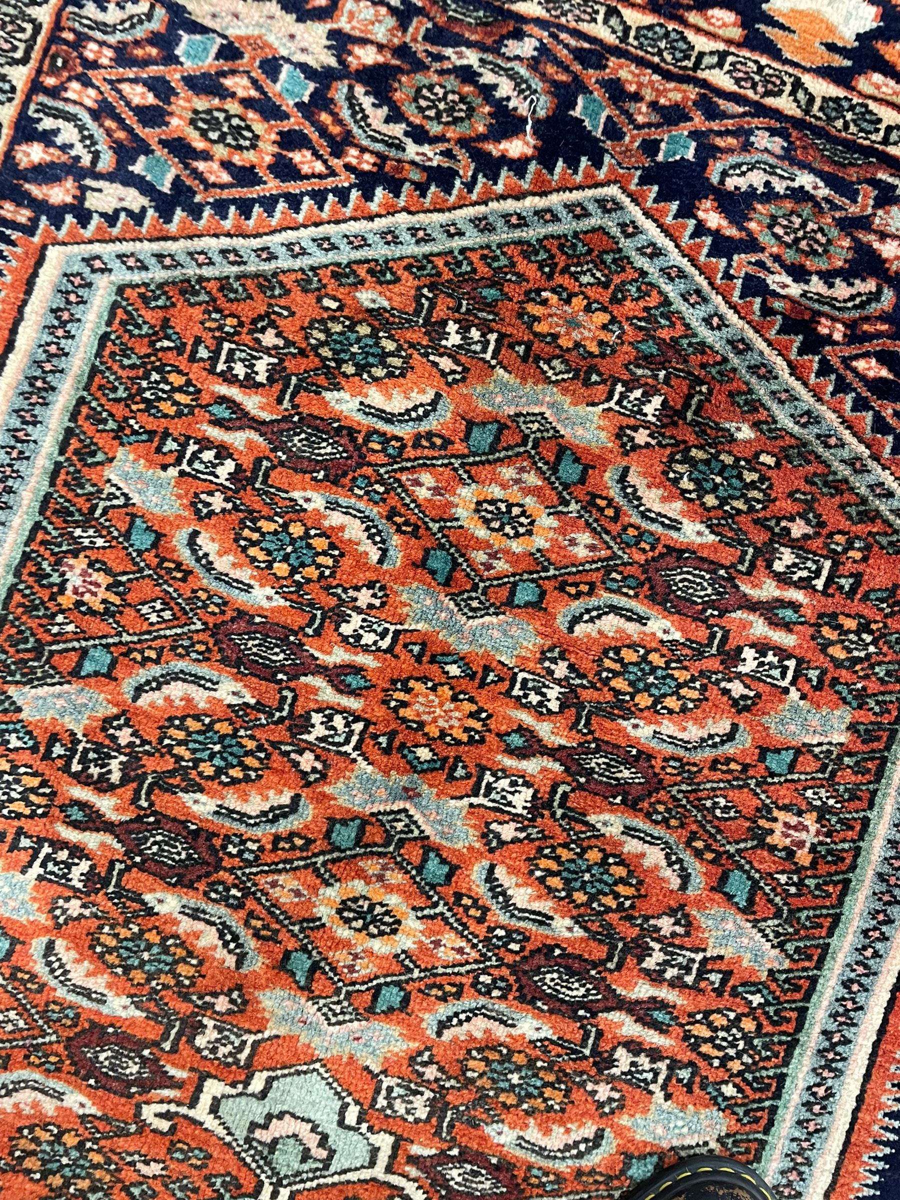 North West Persian Bidjar rug, orange peach ground extended field on indigo ground, decorated with floral Herati motifs, repeating waved border decorated with stylised plant motifs