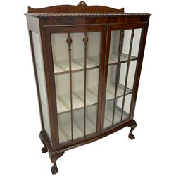 Early 20th century figured walnut bow-front display cabinet, enclosed by two glazed doors, on ball and claw cabriole feet