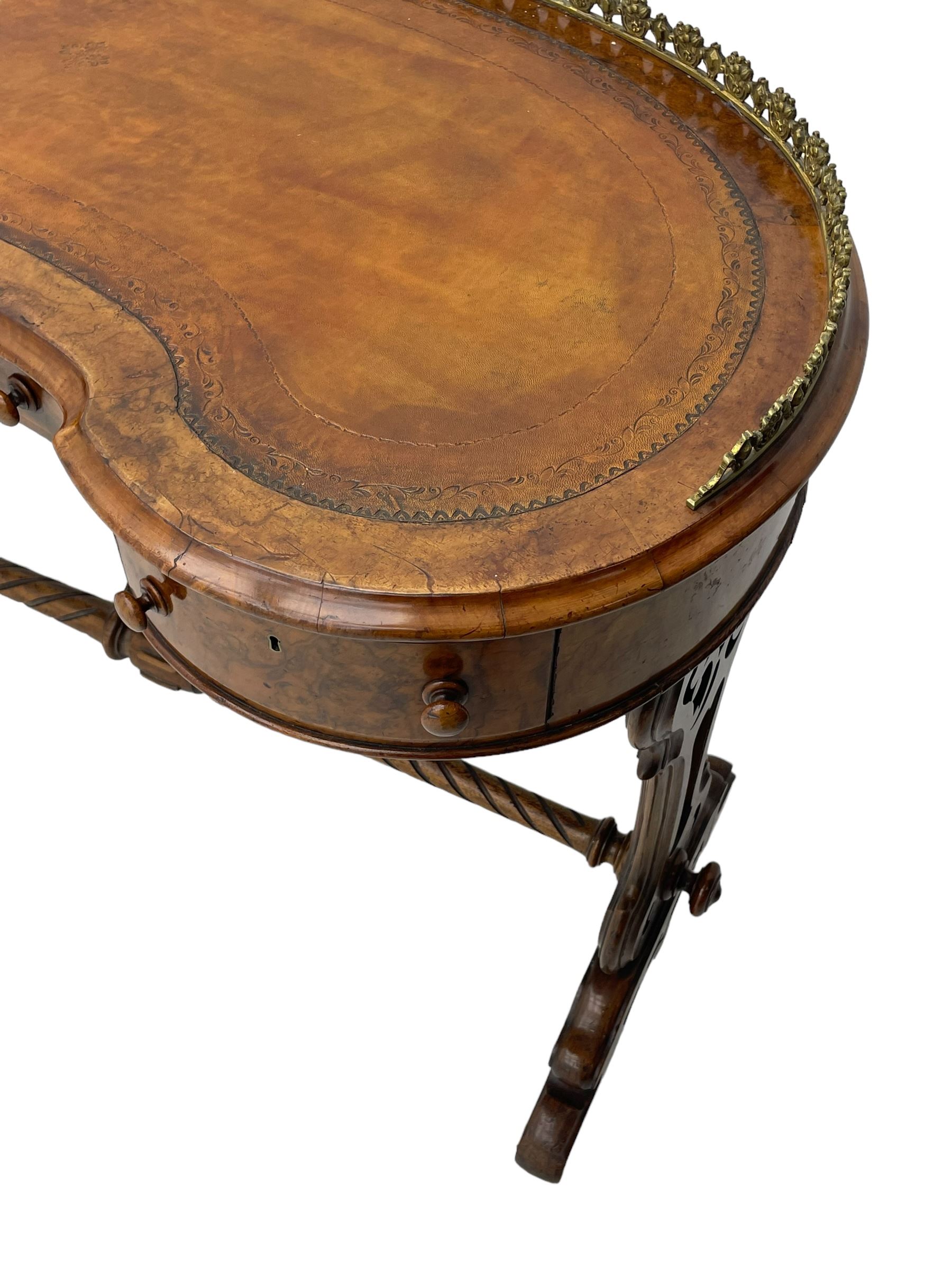 Victorian walnut kidney-shaped writing desk, moulded top with floral cast brass gallery and inset leather writing surface, fitted with three frieze drawers with turned handles, shaped and pierced end supports on raised platforms terminating to splayed feet, united by twist turned and lobe carved stretcher, brass and ceramic castors 