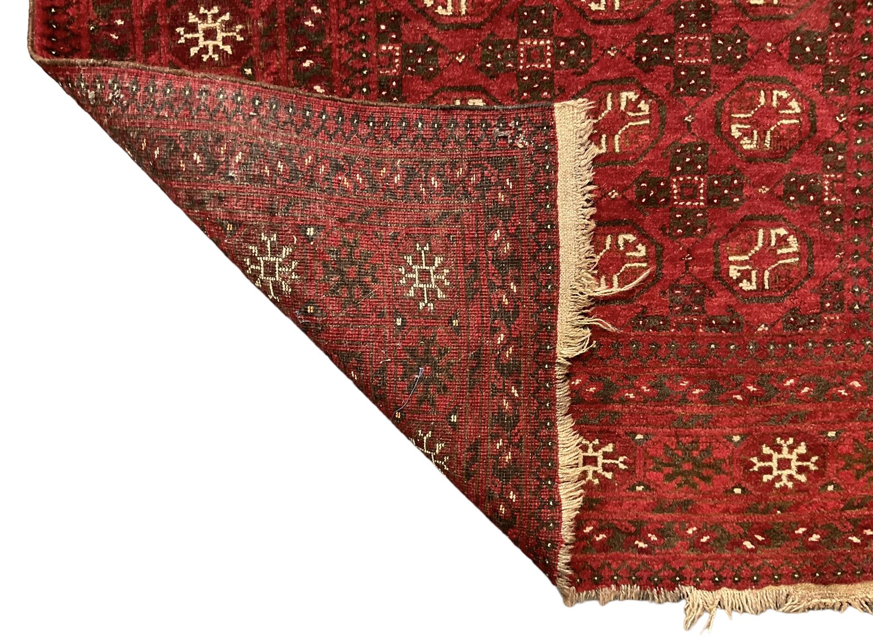 Antique Persian crimson ground rug, the field decorated with Gul motifs, the guarder border with stylised stars in ivory and dark indigo