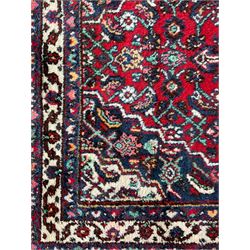 Persian Herati crimson ground rug, central ivory pole medallion surrounded by Herati motifs, with contrasting indigo spandrels, multi-band border with interlaced flowerheads