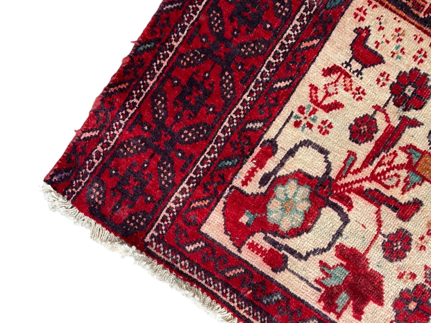 Persian Baluchi dark indigo and crimson ground rug, the field decorated with rows of repeating Pitrak motifs and surrounded by small bird and flower head motifs, floral urn decorated spandrels, repeating Pitrak border within guard stripes