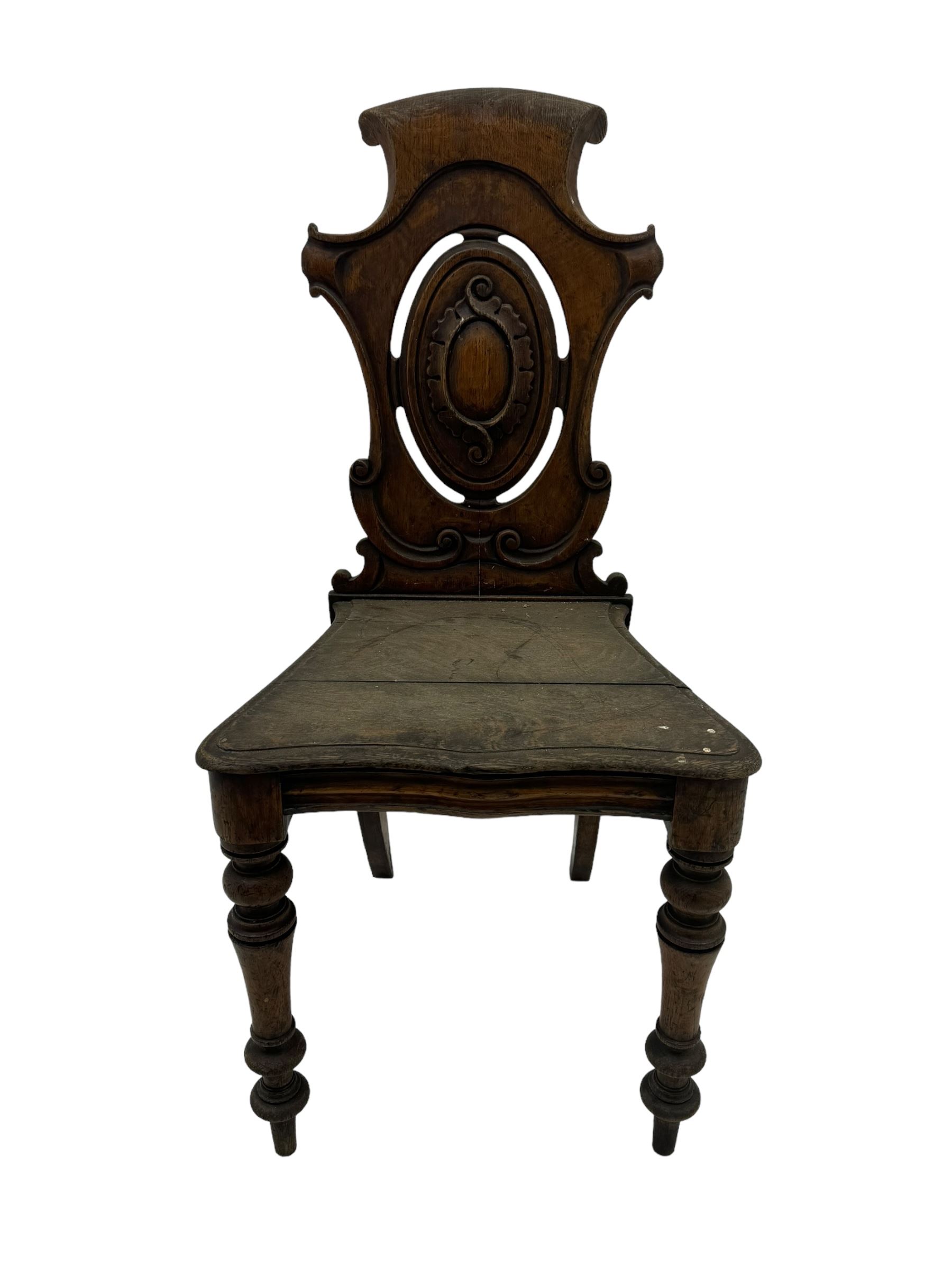 Victorian oak hall chair with scroll carved and pierced back, shaped seat and turned front supports