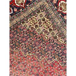 Perisian Bidjar crimson ground rug, within scalloped borders, central pole medallion, the field decorated all over with floral Herati motifs, guarded border decorated with repeating stylised plant motifs and trailing branch 