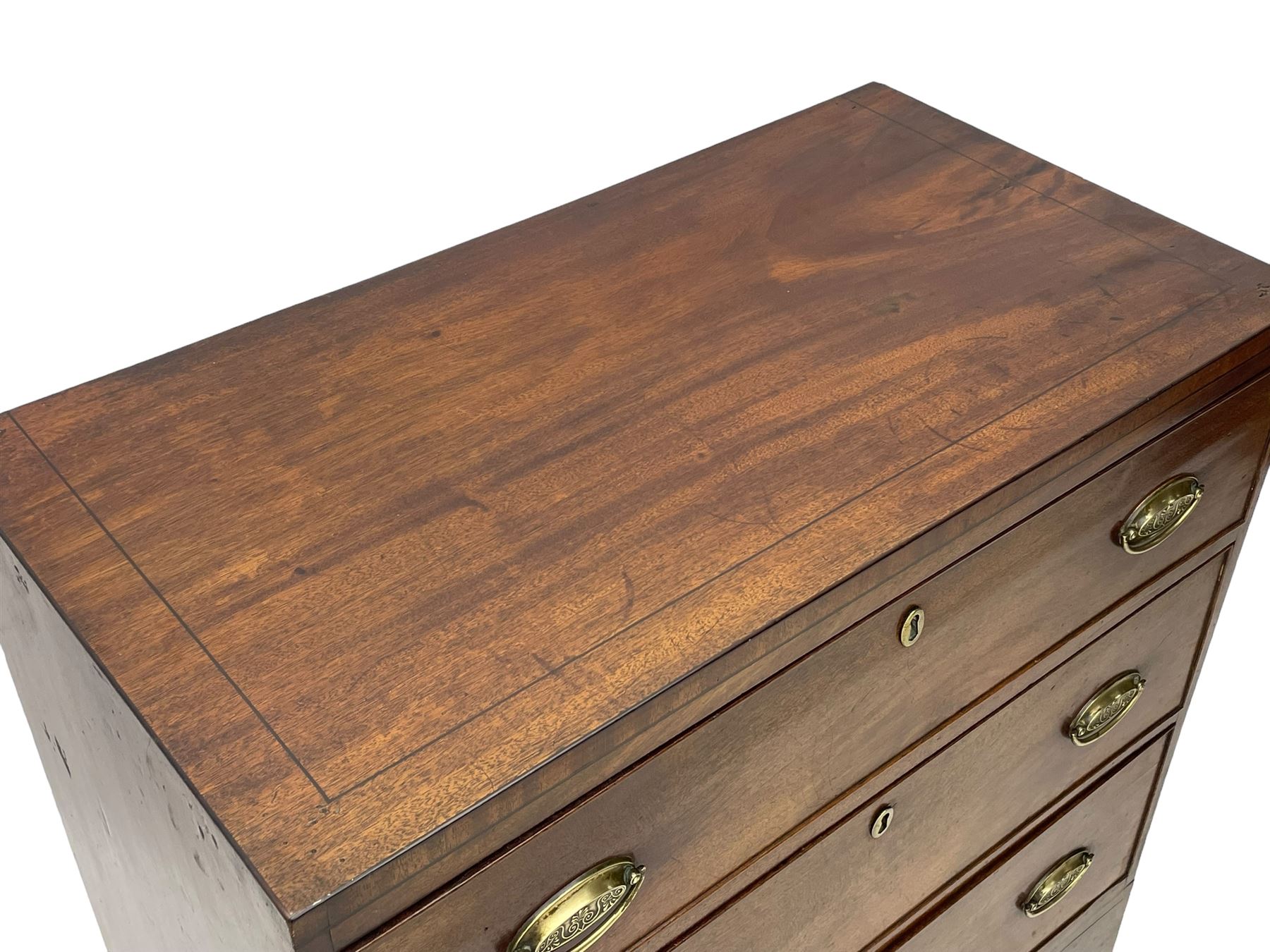 George III mahogany chest, rectangular ebony strung top, fitted with three graduating cock-beaded drawers with oval pressed brass handle plates and demi-lune handles, on tall bracket feet 