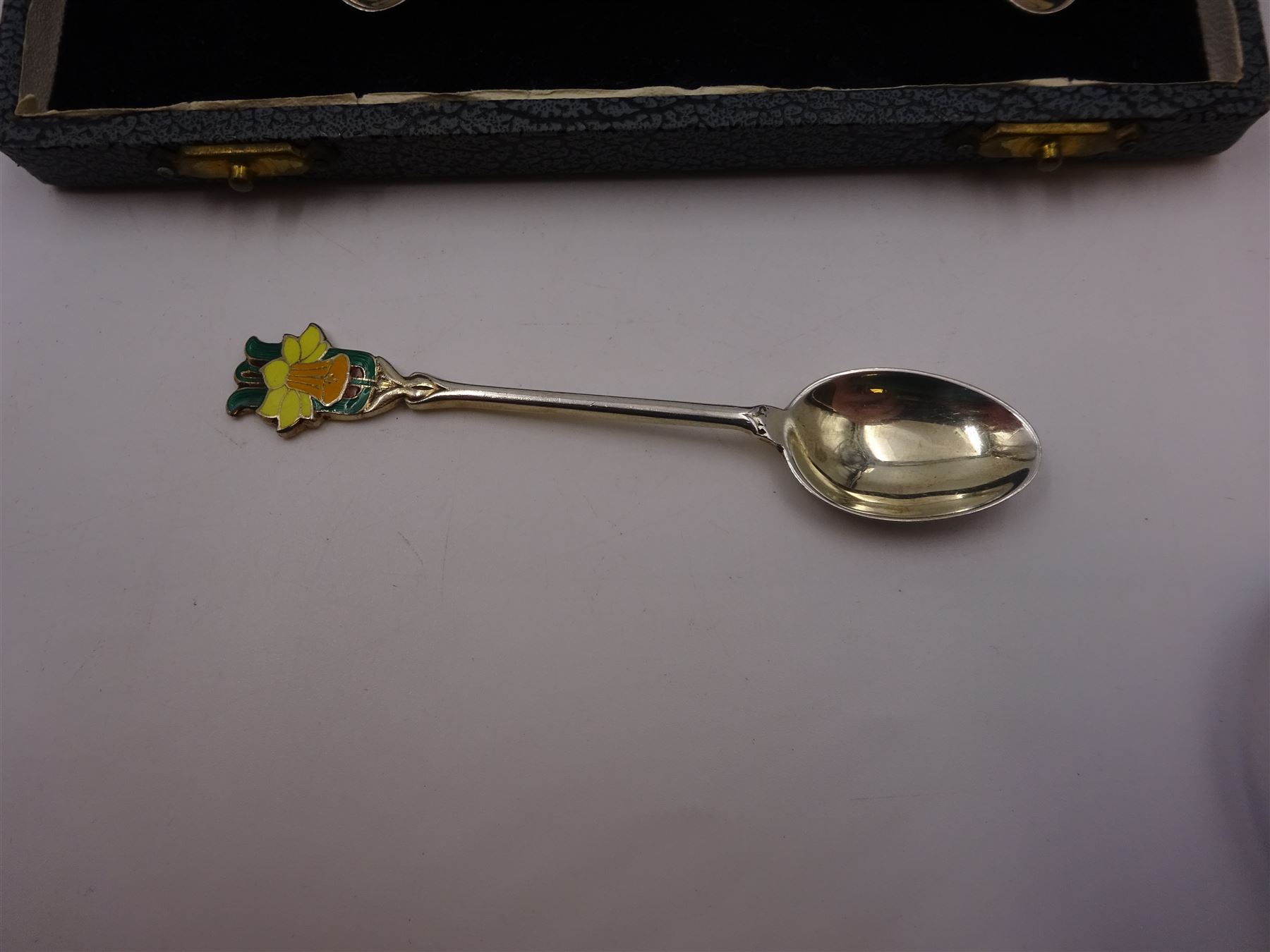 Set of six silver coffee spoons, each with enamelled daffodil decoration to terminal, hallmarked Turner & Simpson Ltd, Birmingham 1938, contained within fitted case