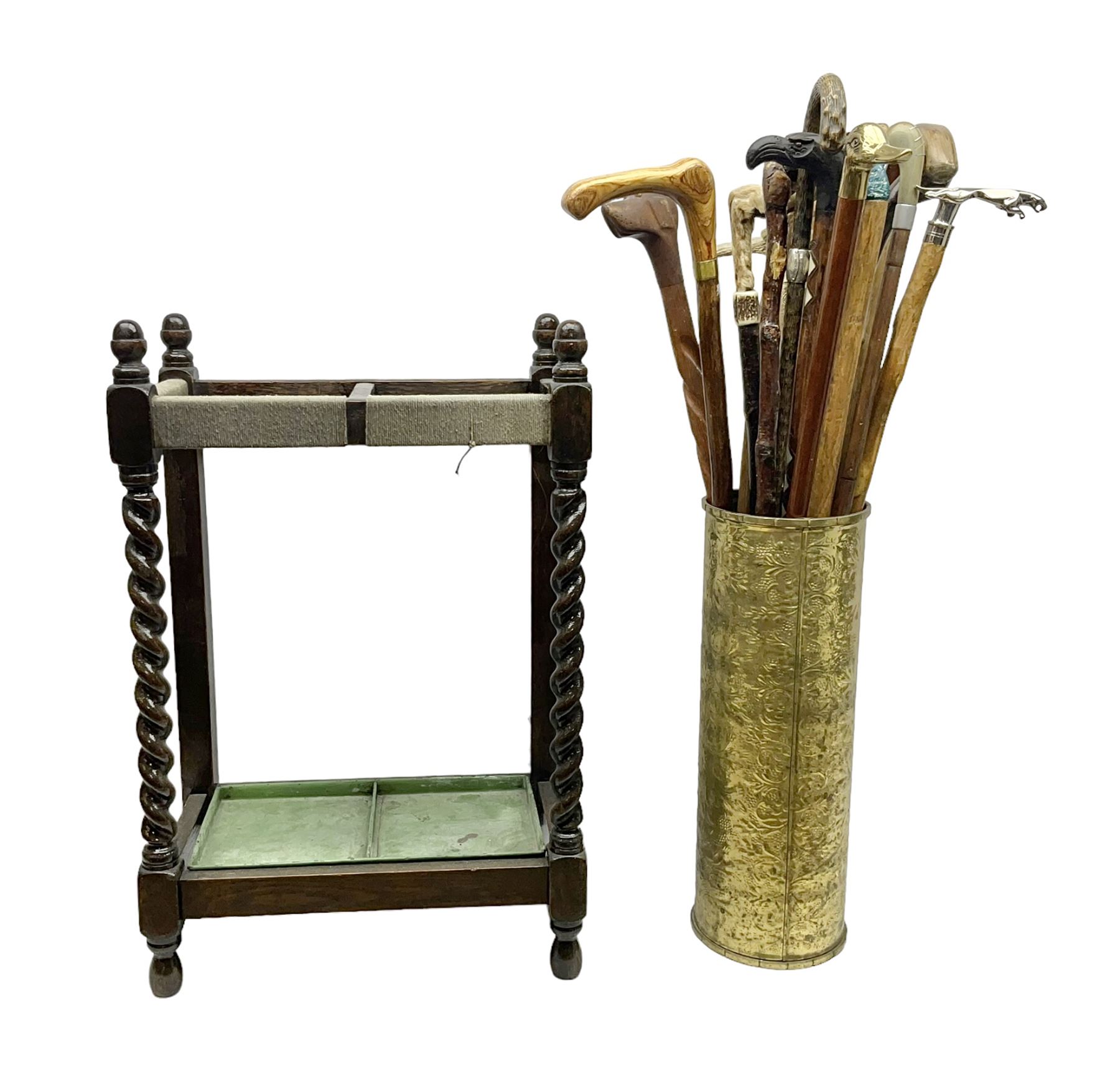 Oak barley twist stick stand, with a collection of walking sticks including examples with carved pommels, horn handles, silver collar etc, together with brass stick stand 