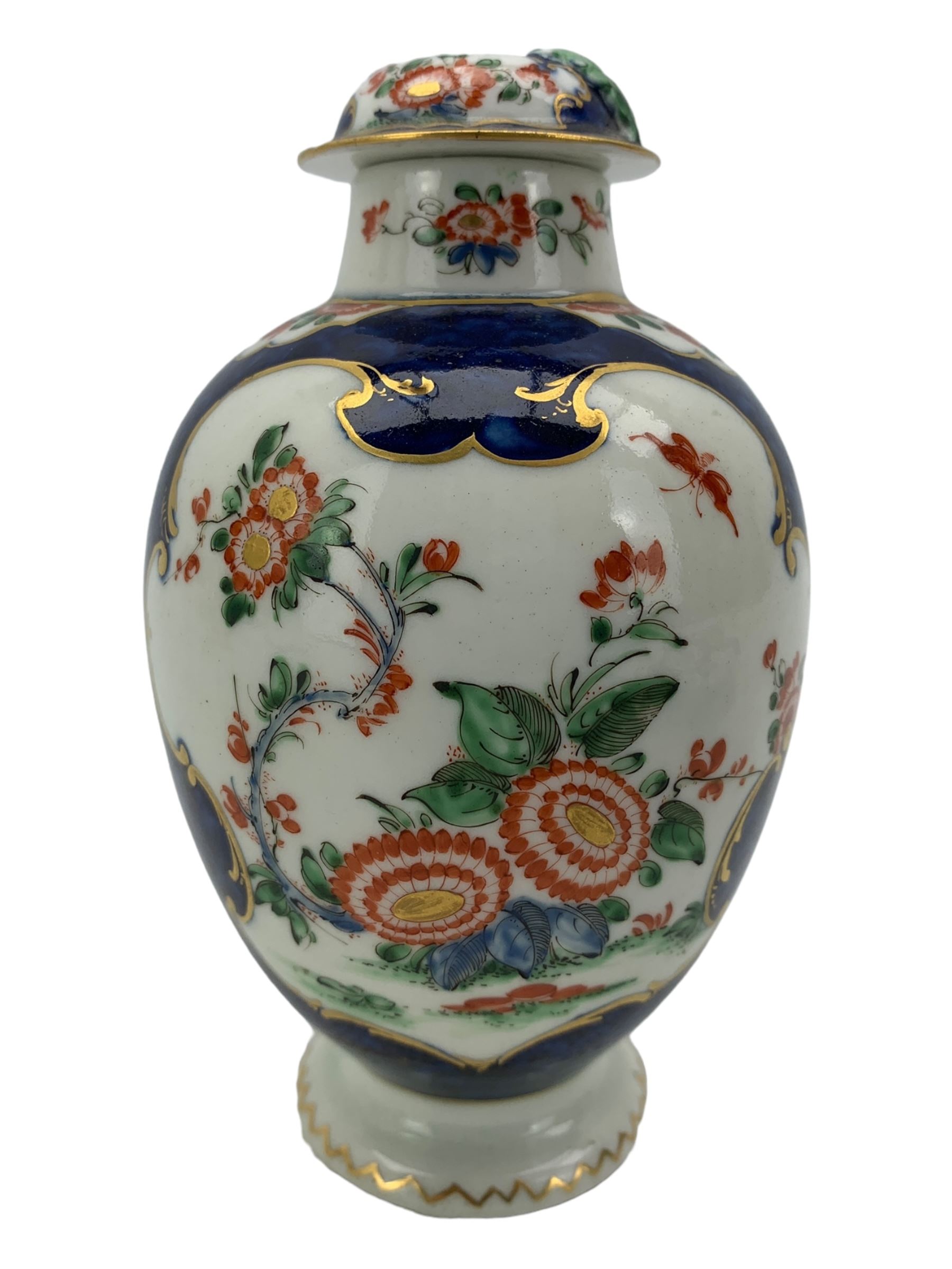 18th century Worcester tea caddy, of oval form and painted in the Kakiemon palette with reserves of flowers against a blue scale ground, H14cm together with a similar Worcester circular dish, painted with floral sprays, within a scalloped edge, blue crescent mark beneath, D19cm (2)