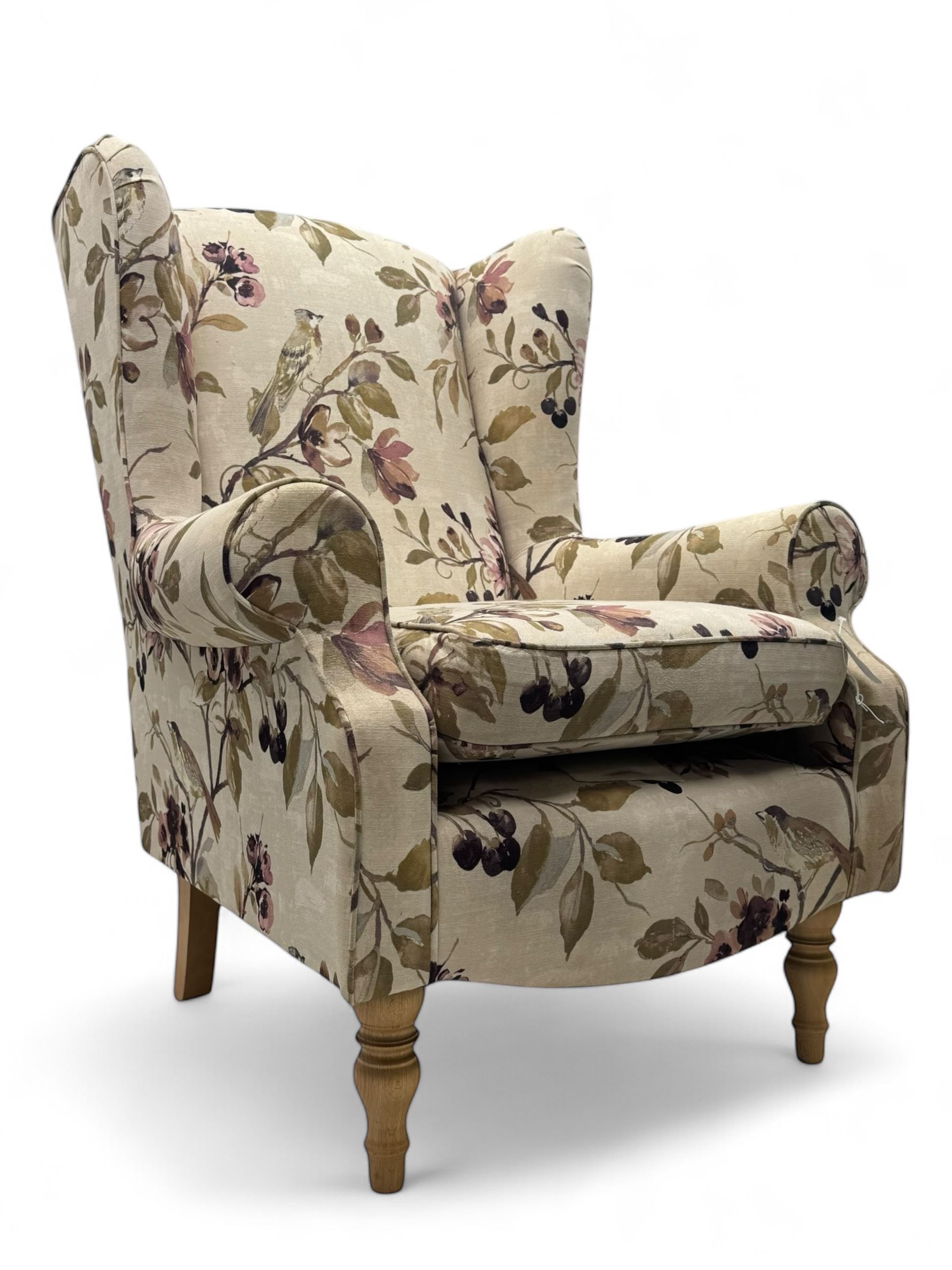 Hardwood-framed wingback armchair, upholstered in cream floral pattern fabric, on turned front feet