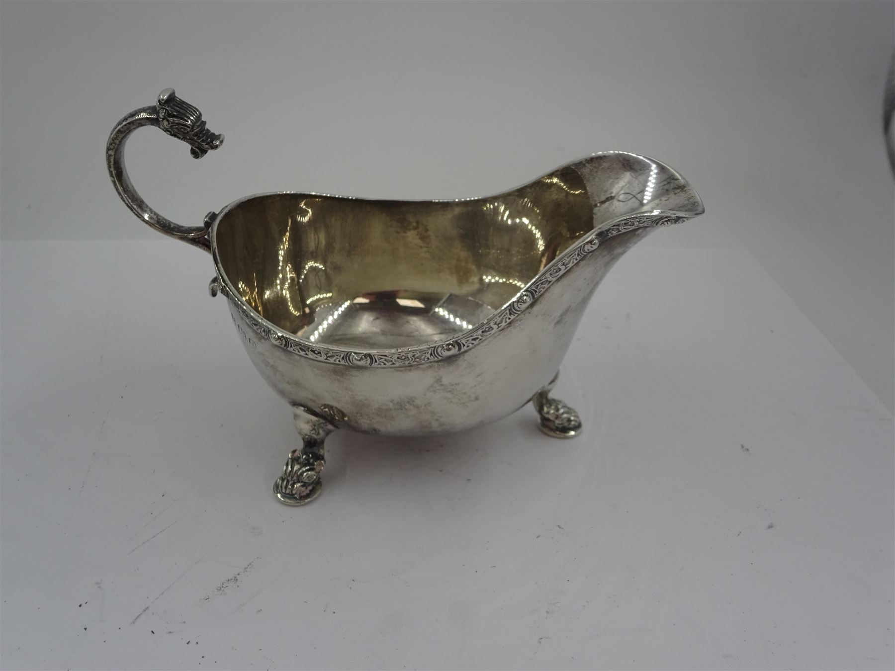 Early 20th century silver sauce boat, of typical form with flying scroll handle, the handle and feet modelled as Viking style dragon heads, hallmarked Adie Brothers Ltd, Birmingham, date mark indistinct, possibly 1940, including handle H9cm