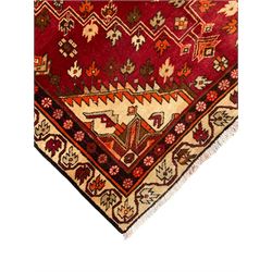 Persian crimson ground rug, the field decorated with three medallions within stepped borders, decorated all over with small stylised plant motifs, trailing flower head outer band and floral pattern border 