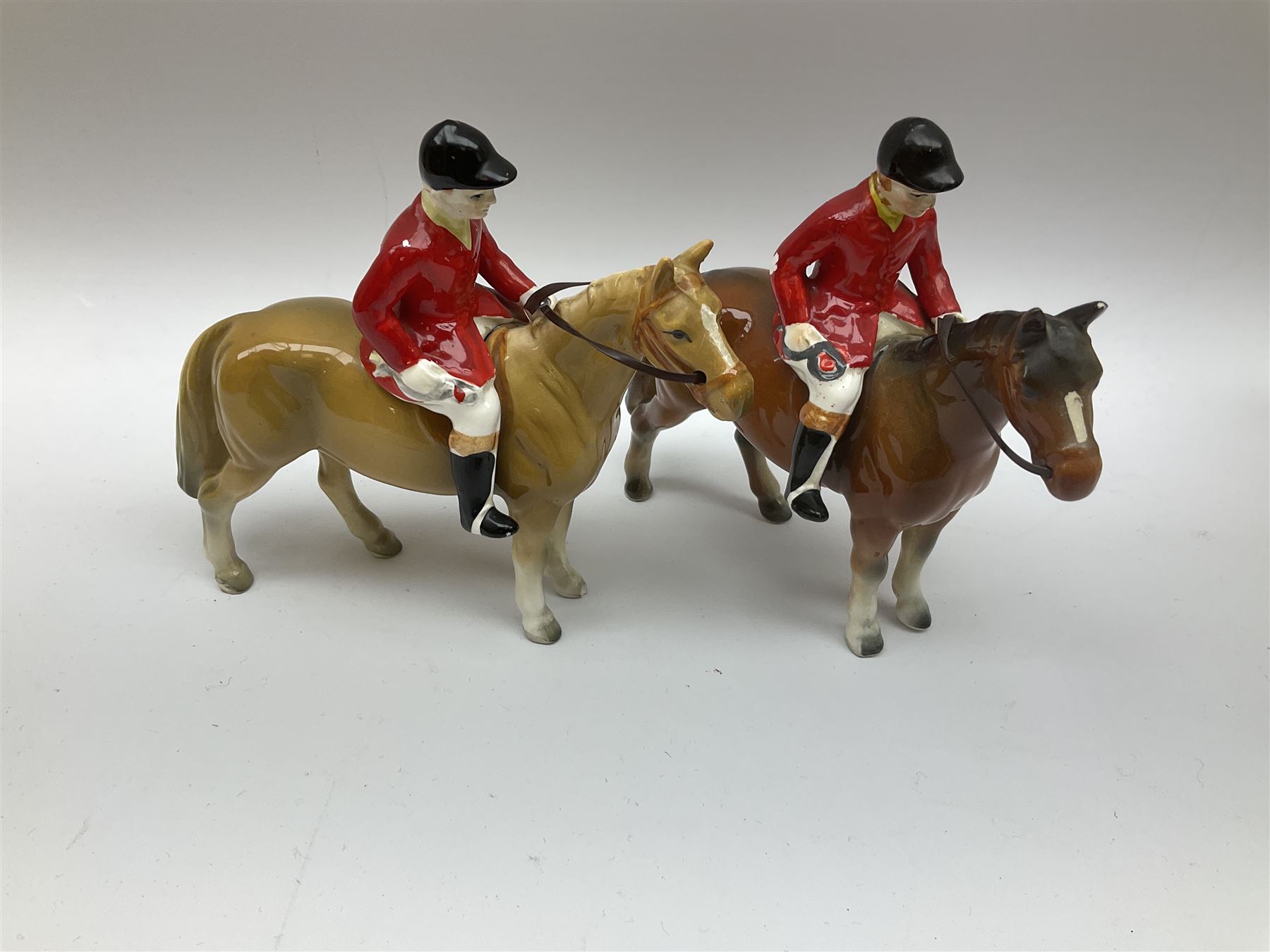 Beswick Hunting Group, comprising: two huntswoman on grey horses, model no 1730, huntsman on a bay horse, model no 1501, a seated fox, model no 1748, eighteen fox hounds and a spaniel, model no 967, all with printed marks beneath, together with three other ceramic huntsman on horseback and two hounds. 