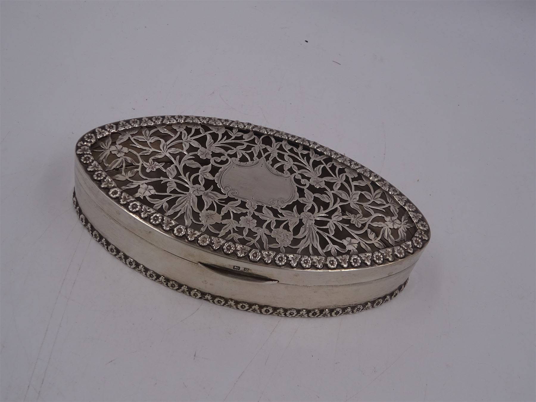 Edwardian silver trinket box, of navette form, the hinged cover with pierced floral and foliate decoration, and blank cartouche, hallmarked George Nathan & Ridley Hayes, Birmingham 1915 and stamped to base Pearce & Sons Silversmiths Leeds & York, W15.5cm, H3.5cm, 