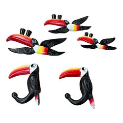 Three cast iron Guinness toucans in flight, together with two cast iron hooks