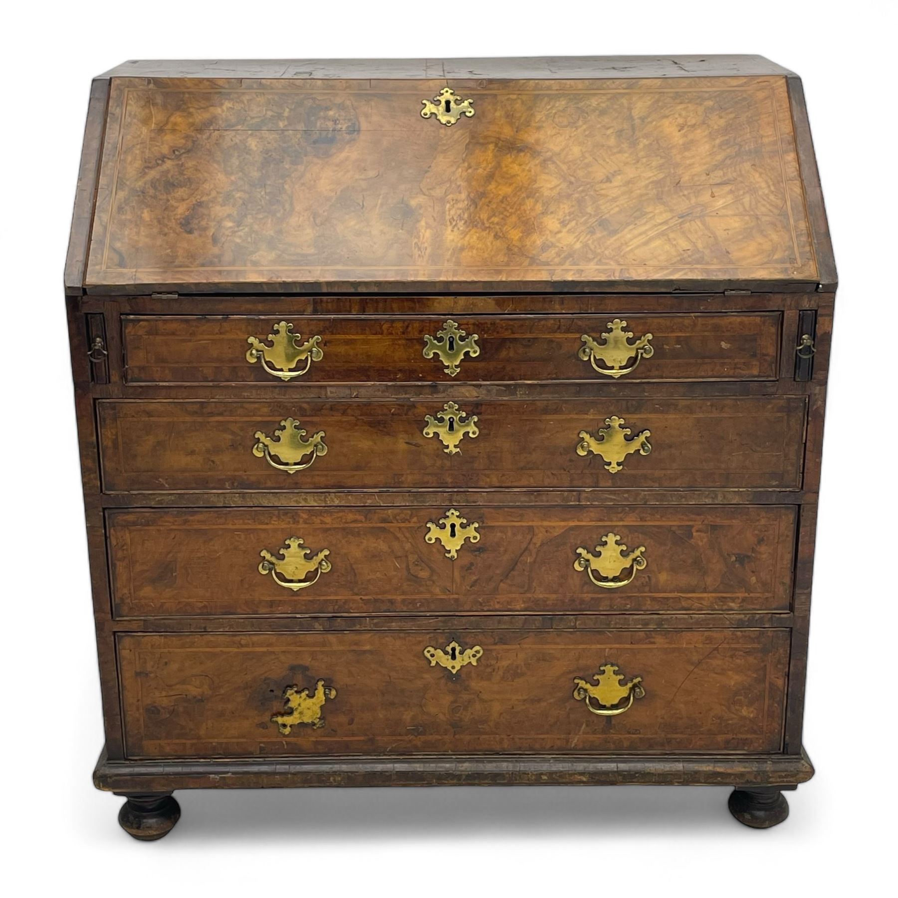 George I figured walnut bureau, hinged fall front enclosing drawers, pigeon holes and slide revealing storage well, fitted with four long cock-beaded and graduating drawers, shaped brass handle plates and escutcheons, on turned bun feet 