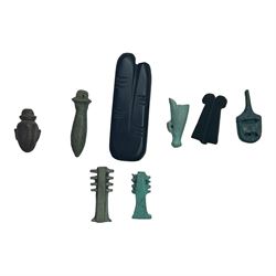 Eight Egyptian amulets, comprising black stone two figure amulet modelled as an outstretched index and middle finger, two faience Djed pillar amulets, obsidian double plume amulet, faience white crown amulet, papyrus amulet, heart amulet, and another blue example, largest two figure amulet L5.5cm