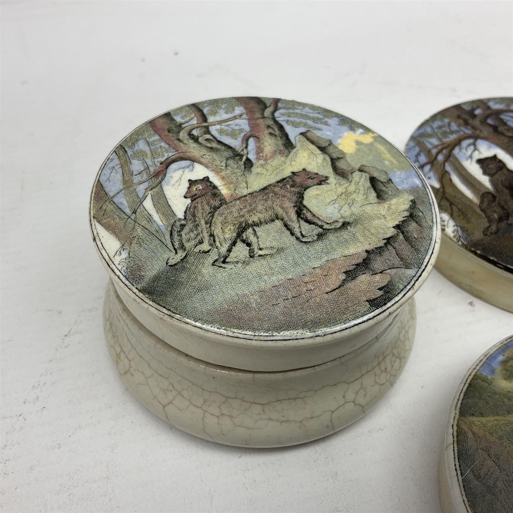 Six 19th century Prattware pot lids comprising 'The Village Wakes', three 'Bear on Rock', 'Shooting Bears' and 'Bear, Lion and Cock', two with associated bases, largest D9cm (6)